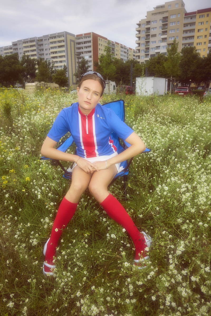 soccer jersey, blue jersey, red socks, field of flowers, urban background