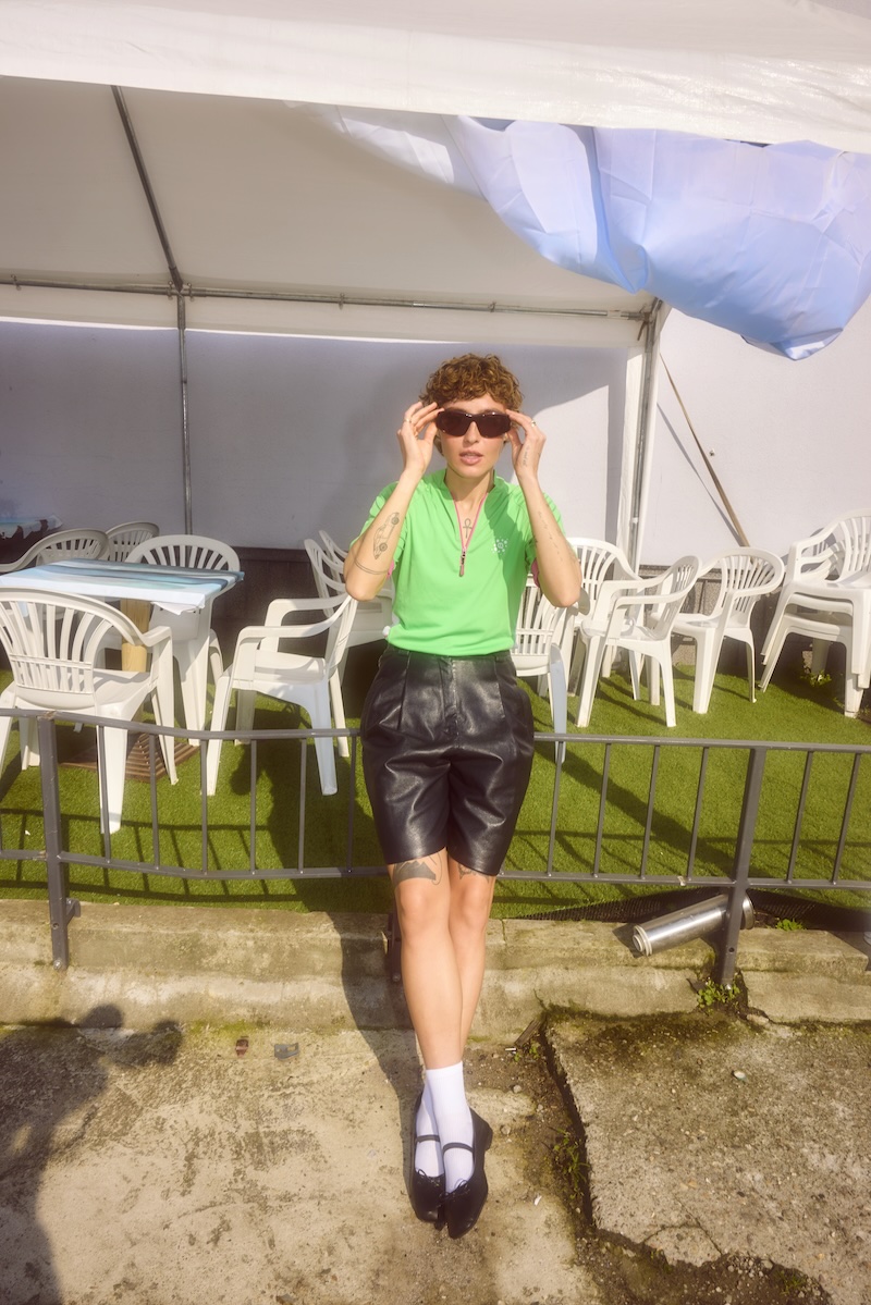 grüne polo, lederrock, kurze haare, sonnenbrille, socken-schuh-kombi